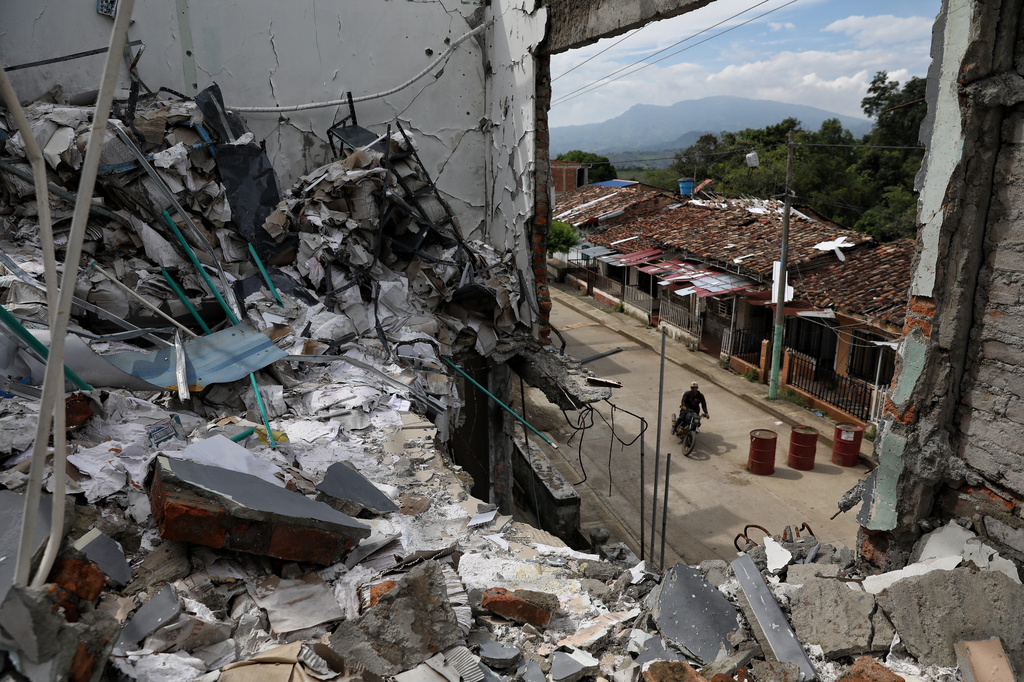A man rides his motorcycle past the ruins of homes destroyed five months earlier in an attack by dissidents of the former Revolutionary Armed Forces of Colombia, or FARC, in Buenos Aires, Cauca, Colombia, Wednesday, May 20, 2026.(AP Photo/Santiago Saldarriaga)