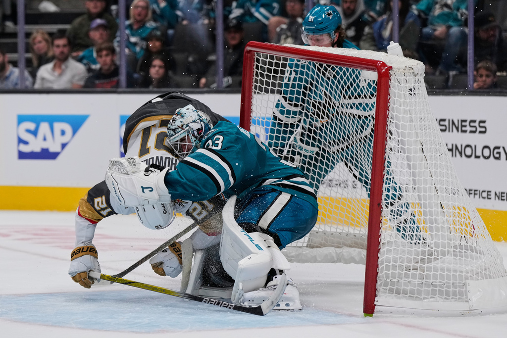 Vegas Golden Knights center Brett Howden (21) collides with San Jose Sharks goaltender Alex Nedeljkovic (33) during the second period of an NHL hockey game Thursday, Oct. 9, 2025, in San Jose, Calif. (AP Photo/Godofredo A. Vásquez)