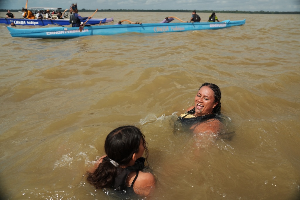 Whaia, from Aotearoa, Māori for New Zealand, right, and her daughter Moana Mason, 8, cool off as they participate in the People's Summit event on Guajara Bay during the COP30 U.N. Climate Summit, Wednesday, Nov. 12, 2025, in Belem, Brazil. (AP Photo/Joshua A. Bickel)