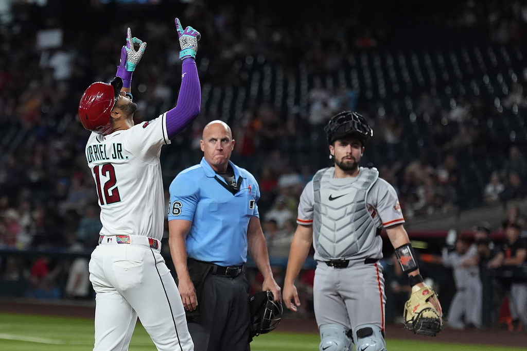 Arizona Diamondbacks' Lourdes Gurriel Jr. (12) celebrates his three-run home run as umpire Ryan Blakney and San Francisco Giants catcher Drew Cavanaugh (61) look on during the first inning of a baseball game, Tuesday, June 30, 2026, in Phoenix. (AP Photo/Ross D. Franklin)