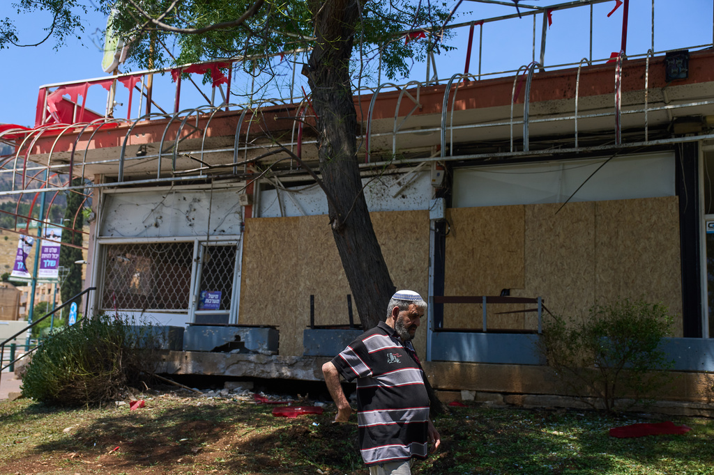 A local resident walks past the site struck by a rocket fired from Lebanon on Saturday in Kiryat Shmona, northern Israel, Sunday, May 31, 2026. (AP Photo/Ariel Schalit)