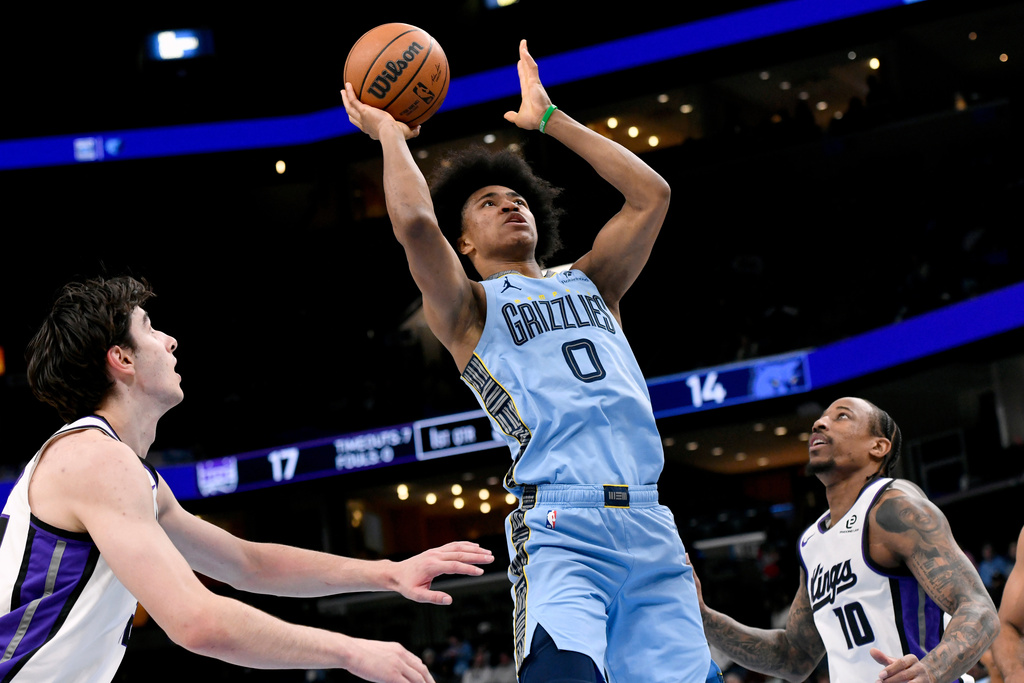 Memphis Grizzlies forward Jaylen Wells (0) shoots between Sacramento Kings center Maxime Raynaud, left, and guard DeMar DeRozan (10) in the first half of an NBA basketball game Monday, Feb. 23, 2026, in Memphis, Tenn. (AP Photo/Brandon Dill)