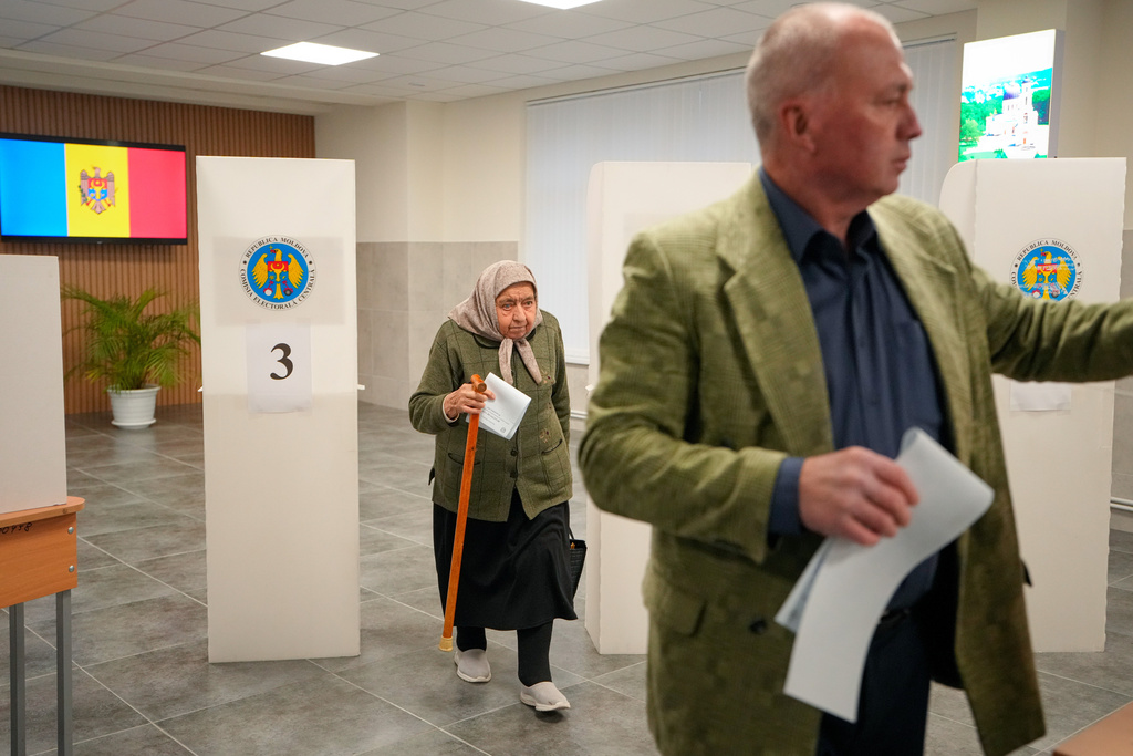 A woman exiting a voting booth waits in line to cast her vote during a parliamentary election, in Chisinau, Moldova, Sunday, Sept. 28, 2025. (AP Photo/Vadim Ghirda)