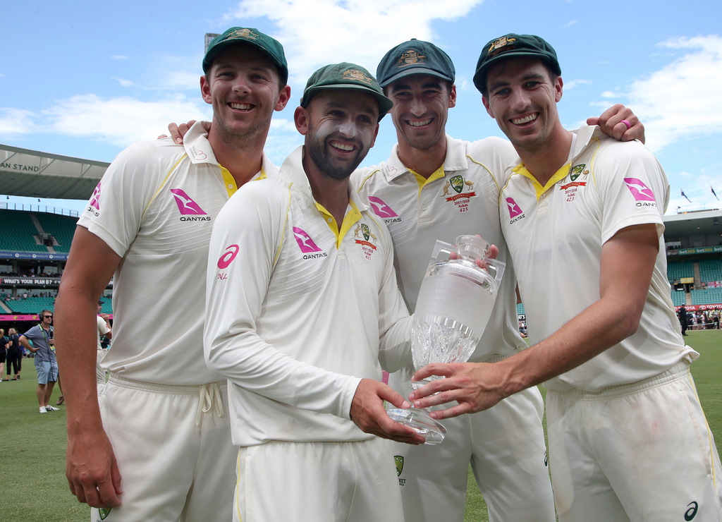 FILE - Australian bowlers Josh Hazlewood, left, Nathan Lyon, Mitchell Starc, second right, and Pat Cummins, right, hold the Ashes trophy as they celebrate at the end the last day of their Ashes cricket test match against England in Sydney, Jan. 8, 2018. (AP Photo/Rick Rycroft, File)