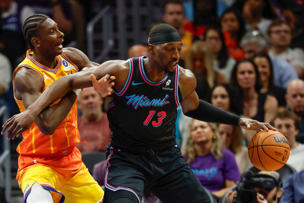 Miami Heat center Bam Adebayo (13) moves the ball against Charlotte Hornets forward Moussa Diabate, left, during the first half of an NBA basketball game in Charlotte, N.C., Friday, March 6, 2026. (AP Photo/Nell Redmond)