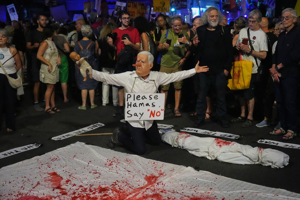A demonstrator wears a mask depicting Israeli Prime Minister Benjamin Netanyahu during a protest calling for the immediate release of all hostages held by Hamas in the Gaza Strip and an end to the ongoing war, in Tel Aviv, Israel, Tuesday, Sept. 30, 2025, (AP Photo/Ariel Schalit)