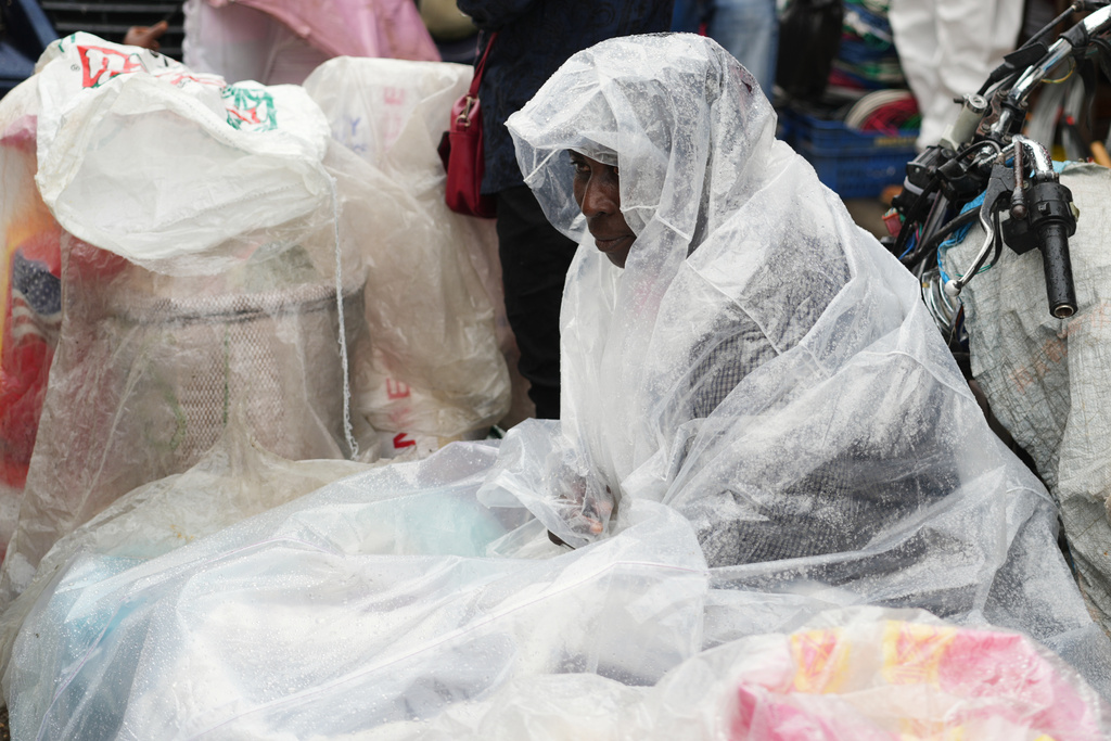 A street vendor covers up in plastic during a light rain in the Petion-Ville neighborhood of Port-au-Prince, Haiti, Tuesday, Oct. 28, 2025, as Hurricane Melissa passes through the Caribbean. (AP Photo/Odelyn Joseph)