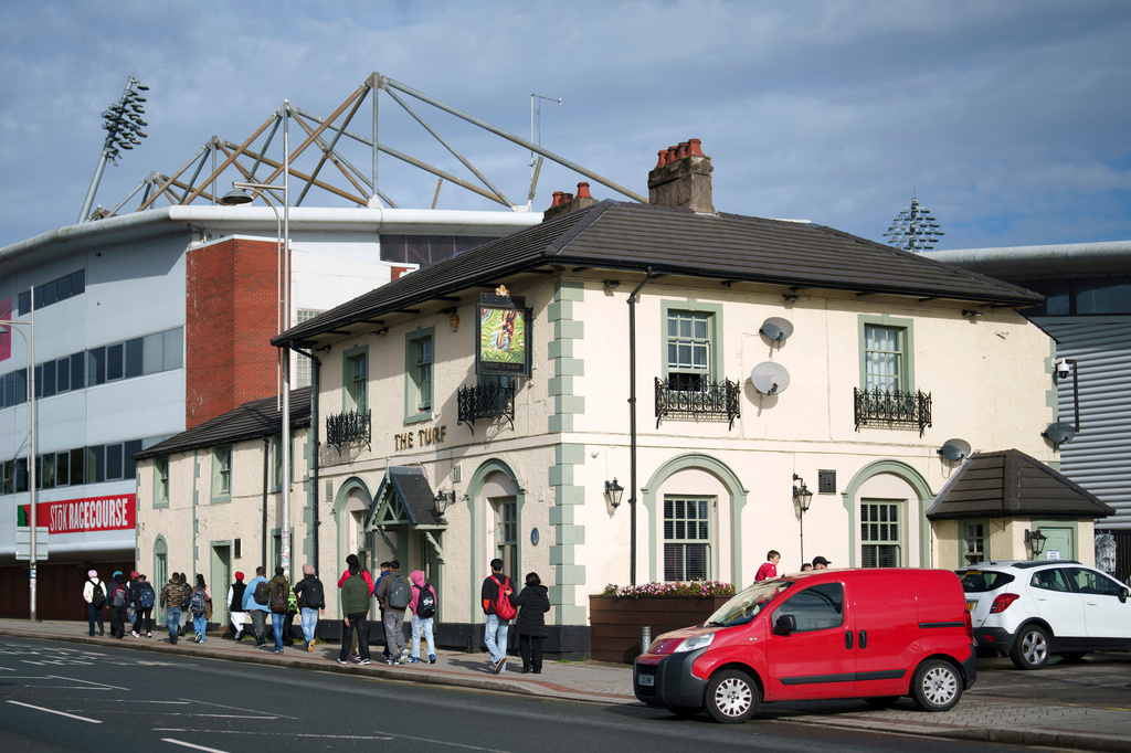 FILE - Members of the public walk past the Turf Pub next to Wrexham Football Club's Racecourse Ground in Wrexham, Wales, Monday, Oct. 7, 2024. (AP Photo/Jon Super, File)