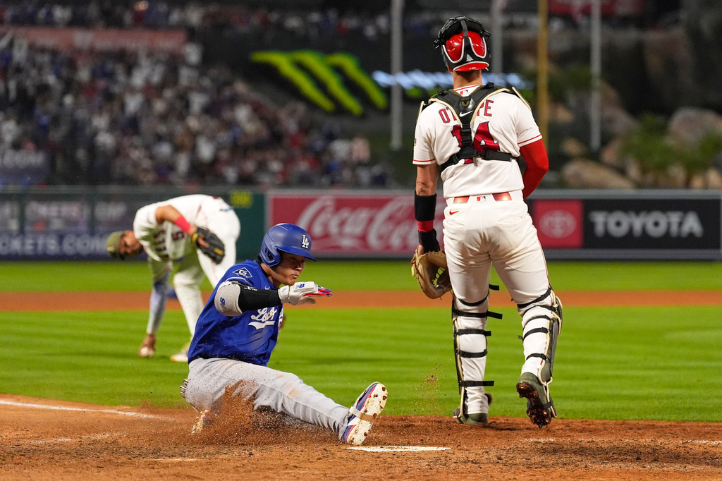 Los Angeles Dodgers' Shohei Ohtani, center, scores on his two-run triple after a throwing error as Los Angeles Angels catcher Logan O'Hoppe, right, stands at the plate and third baseman Vaughn Grissom picks up the ball during the eighth inning of a baseball game Saturday, May 16, 2026, in Anaheim, Calif. (AP Photo/Mark J. Terrill) CORRECTION: After official review, changed from three-run inside-the-park home run to two-run triple after a throwing error