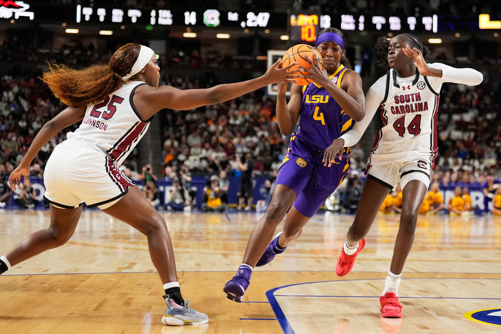 LSU guard Flau'jae Johnson drives to the basket between South Carolina guard Raven Johnson and guard Agot Makeer during the first half of an NCAA college basketball game in the semifinals of the Southeastern Conference tournament, Saturday, March 7, 2026, in Greenville, S.C. (AP Photo/Chris Carlson)