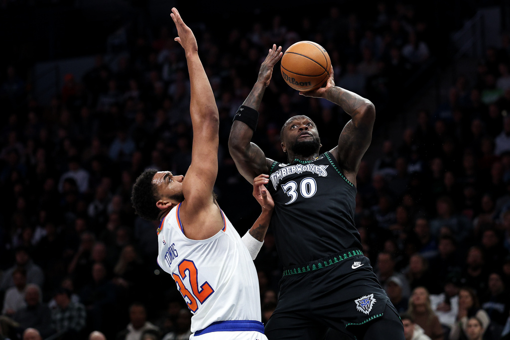Minnesota Timberwolves forward Julius Randle, right, shoots the ball over New York Knicks center Karl-Anthony Towns (32) during the first half of an NBA basketball game Tuesday, Dec. 23, 2025, in Minneapolis. (AP Photo/Matt Krohn)