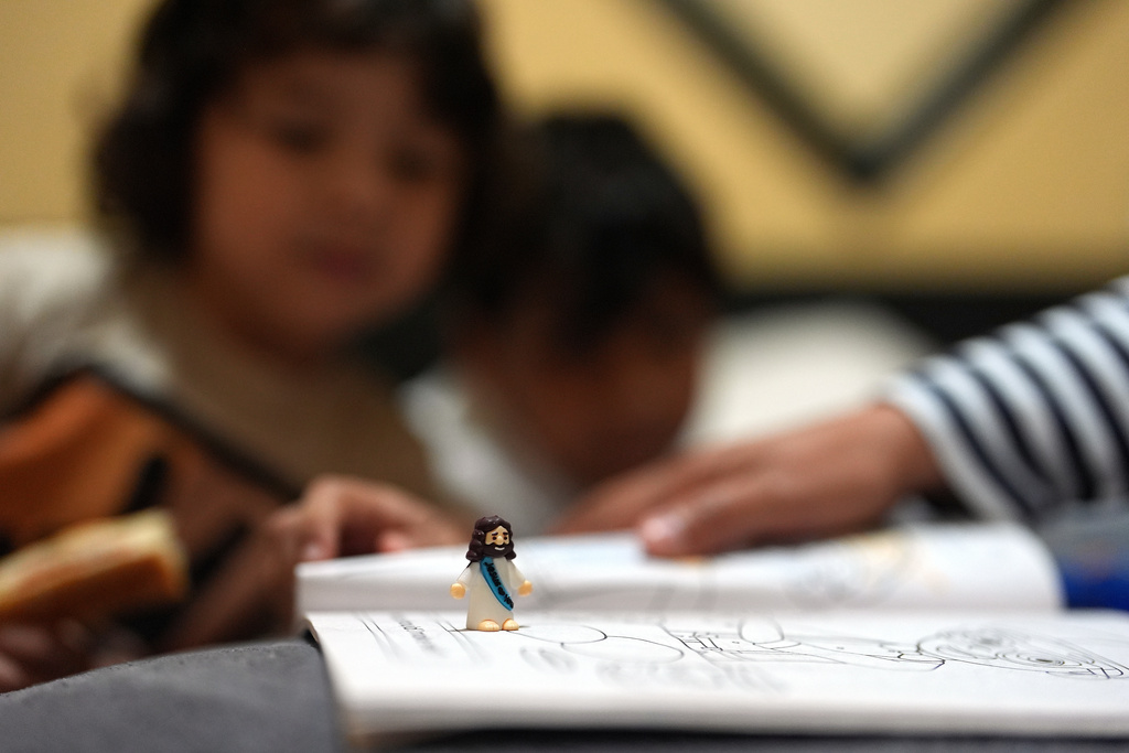 A miniature Jesus figurine sits on a coloring book inside the Miami-area motel room where Jakelin Pasedo is living with her two sons, who all have refugee status, Wednesday, Oct. 22, 2025, after their father requested to be sent back to Venezuela after months in immigration detention. (AP Photo/Rebecca Blackwell)