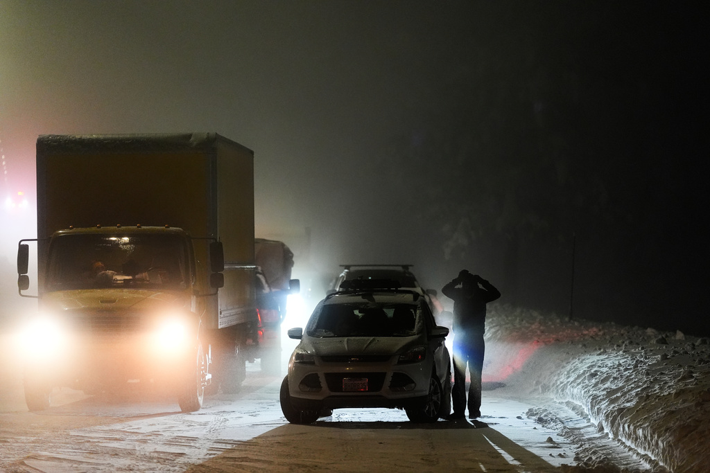 A motorist exits a vehicle during a snow storm Wednesday, Feb. 18, 2026, in Placer County, Calif. (AP Photo/Godofredo A. Vásquez)