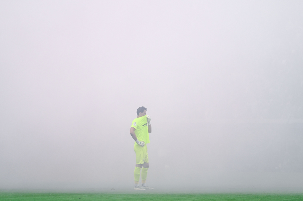 SV Waldhof Mannheim goalkeeper Thijmen Nijhuis covers his face as smoke caused by pyrotechnics lit by fans blankets the stadium during the Germany Cup soccer match between SV Waldhof Mannheim and 1. FC Kaiserslautern, Friday, Aug. 21, 2026, in Mannheim, Germany. (Uwe Anspach/dpa via AP)