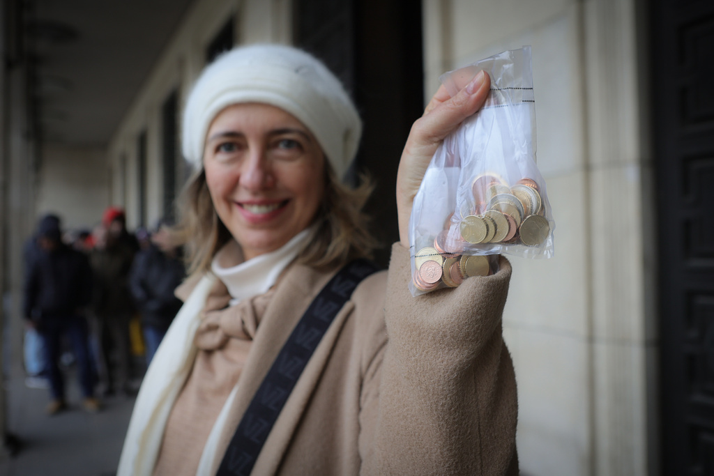 A woman poses as she holds new euro coins with Bulgarian symbols in Sofia in front of Bulgarian National Bank, Saturday Dec. 27, 2025. (AP Photo/Valentina Petrova)