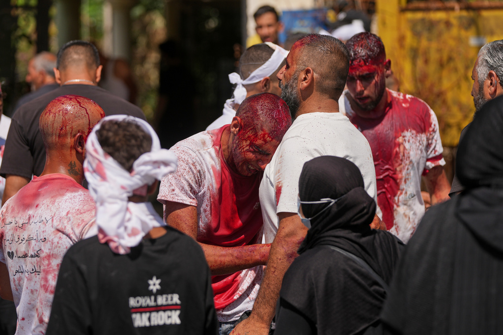 EDS NOTE: GRAPHIC CONTENT - A Lebanese Shiite weeps for a friend killed during the war as he bleeds from a self-inflicted ceremonial head wound during Ashoura, when Shiites commemorate the martyrdom of Imam Hussein, the grandson of the Prophet Muhammad, in Nabatiyeh, southern Lebanon, Friday, June 26, 2026. (AP Photo/Hassan Ammar)