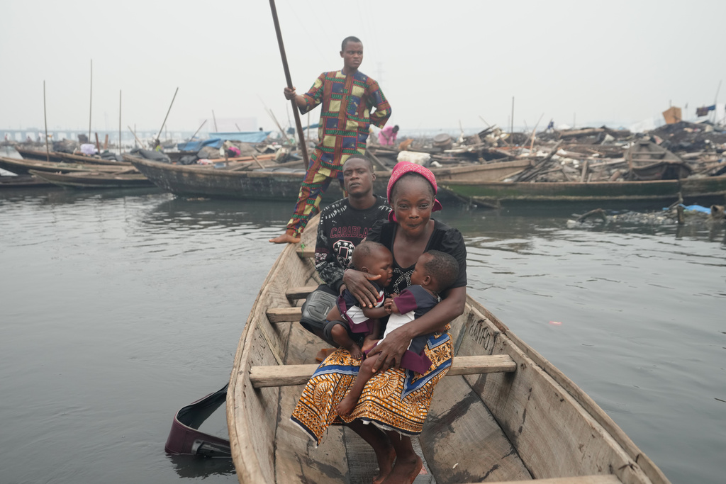 Victor Ahansu, center, and his wife Josianua Agbokpasu, front, ride with their twins inside a canoe in Makoko in Lagos, Nigeria, Friday, Jan.30, 2026. (AP Photo/Sunday Alamba)