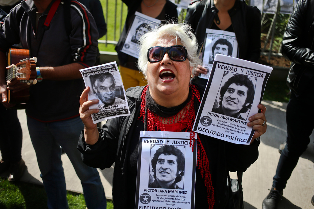 FILE -Members of the Funa Commission shout slogans outside the home of Edwin Dimter Bianchi, accused and on trial for the murder of Chilean singer-songwriter Victor Jara, during a demonstration to publicly shame him in Santiago, Chile, April 22, 2017. (AP Photo/Esteban Felix, File)