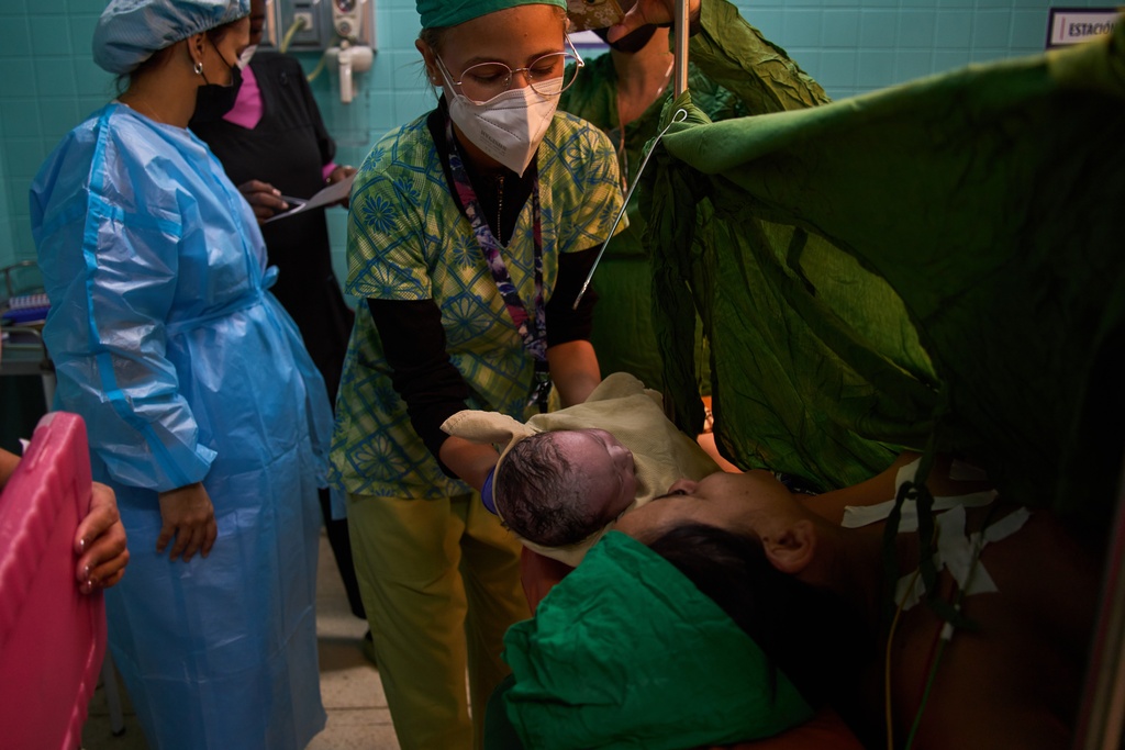 A doctor hands Daimara de la Fe Viera her newborn baby at the Ramón González Coro Maternity Hospital in Havana, Cuba, Friday, Feb. 20, 2026. (AP Photo/Ramon Espinosa)