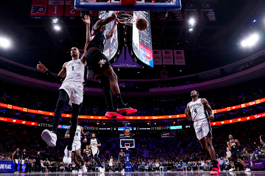 Philadelphia 76ers' VJ Edgecombe, center, dunks the ball as San Antonio Spurs' Victor Wembanyama, left, comes over to defend during the first half of an NBA basketball game, Tuesday, March 3, 2026, in Philadelphia. (AP Photo/Chris Szagola)