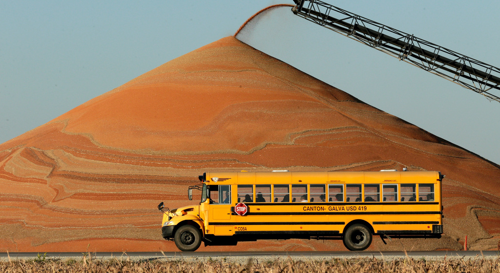 FILE - A school bus passes a pile of milo at a grain storage facility near Canton, Kan., Nov. 10, 2015. (AP Photo/Charlie Riedel, File)