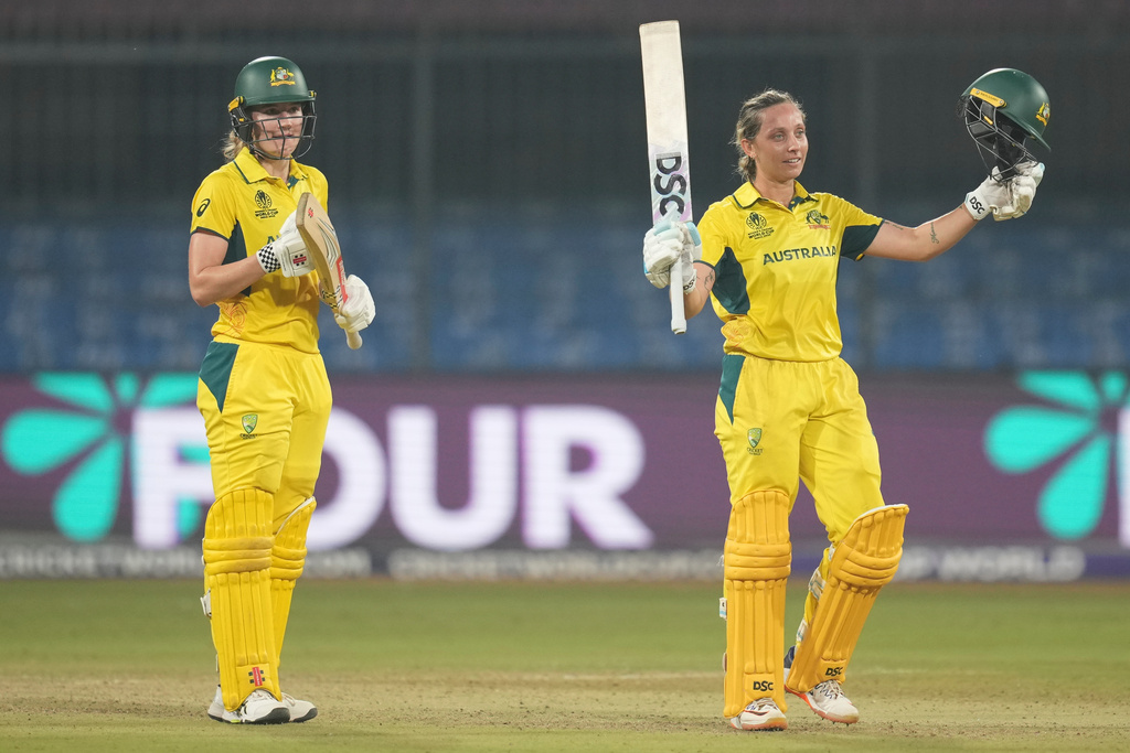 Australia's Ashleigh Gardner, right, celebrates her century as Australia's Annabel Sutherland, left, applauds during the ICC Women's Cricket World Cup cricket match between England and Australia at Holkar Cricket Stadium in Indore, India, Wednesday, Oct. 22, 2025. (AP Photo/Rafiq Maqbool)