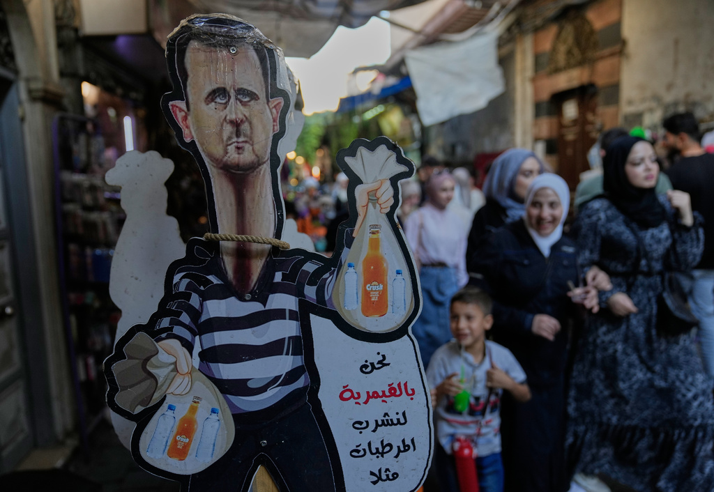A cutout caricature shows the former Syrian president Bashar Assad sells soft drinks in the old city of Damascus, Syria, Thursday, Oct. 2, 2025. (AP Photo/Hussein Malla)