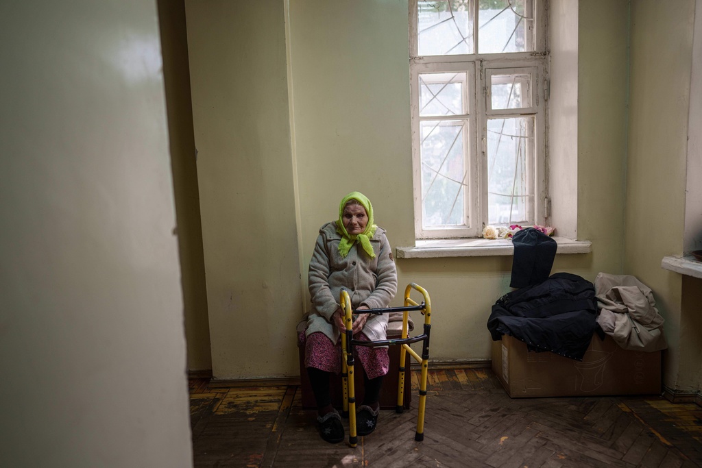 Oleksandra Bezshapko, 91, sits in the corridor of a hostel for displaced people in Dnipro, Ukraine, Wednesday, Oct. 8, 2025. (AP Photo/Evgeniy Maloletka)
