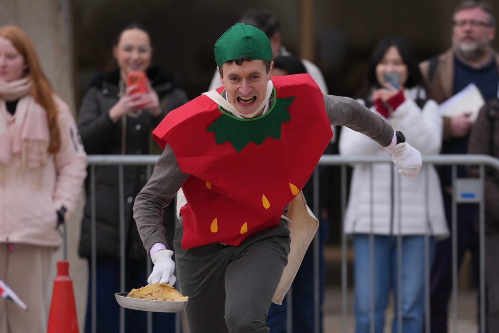 Competitors participate a traditional pancake race by livery companies at the Guildhall in London, Tuesday, Feb. 17, 2026. (AP Photo/Kin Cheung)