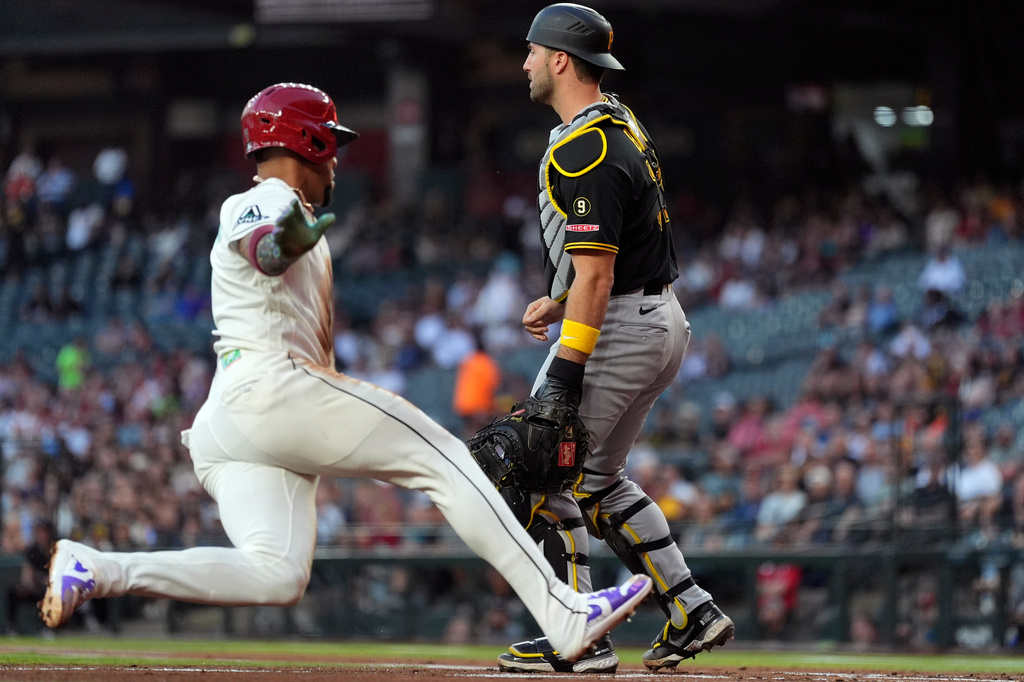 Arizona Diamondbacks' Ketel Marte, left, scores a run as Pittsburgh Pirates catcher Joey Bart waits for a late throw during the first inning of a baseball game, Tuesday, May 5, 2026, in Phoenix. (AP Photo/Ross D. Franklin)