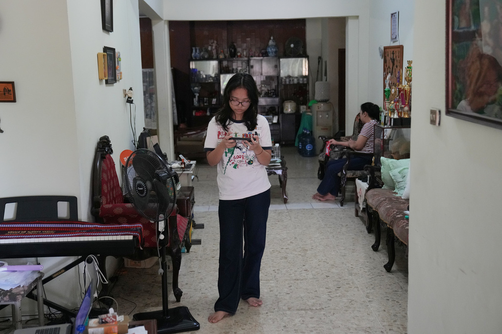 Maura Munthe plays Roblox on her mobile phone at her house in Jakarta, Indonesia, March 14, 2026. (AP Photo/Dita Alangkara)