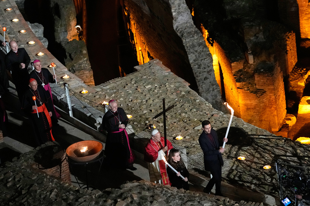 Pope Leo XIV carries a lightweight, 1.5-meter (5-foot) wooden cross during the Via Crucis, the torchlit Good Friday Stations of the Cross procession at the Colosseum in Rome, Friday, April 3, 2026, which symbolically retraces Jesus Christ's steps to his crucifixion on Calvary in Jerusalem. (AP Photo/Alessandra Tarantino)