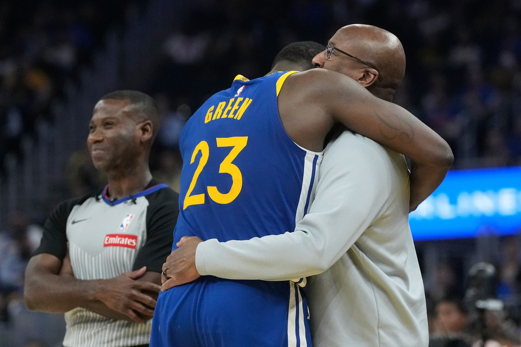 Referee James Williams, left, reacts as Golden State Warriors forward Draymond Green (23) hugs New York Knicks head coach Mike Brown during the first half of an NBA basketball game in San Francisco, Thursday, Jan. 15, 2026. (AP Photo/Jeff Chiu)