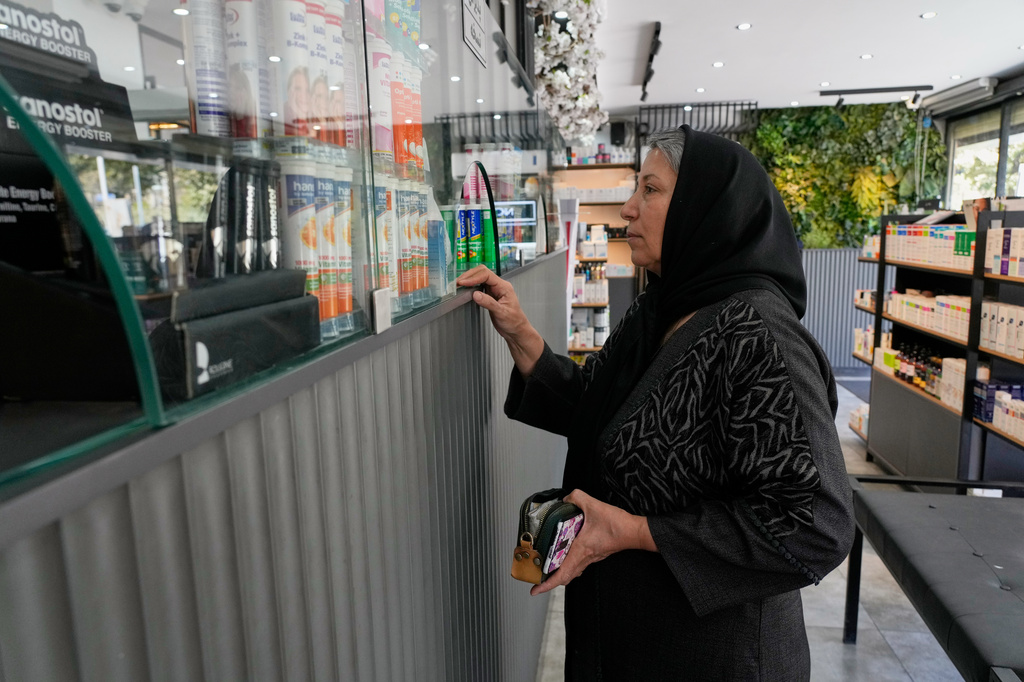 A woman receives her medicine at a pharmacy in Tehran, Iran, Friday, Aug. 21, 2026. (AP Photo/Vahid Salemi)