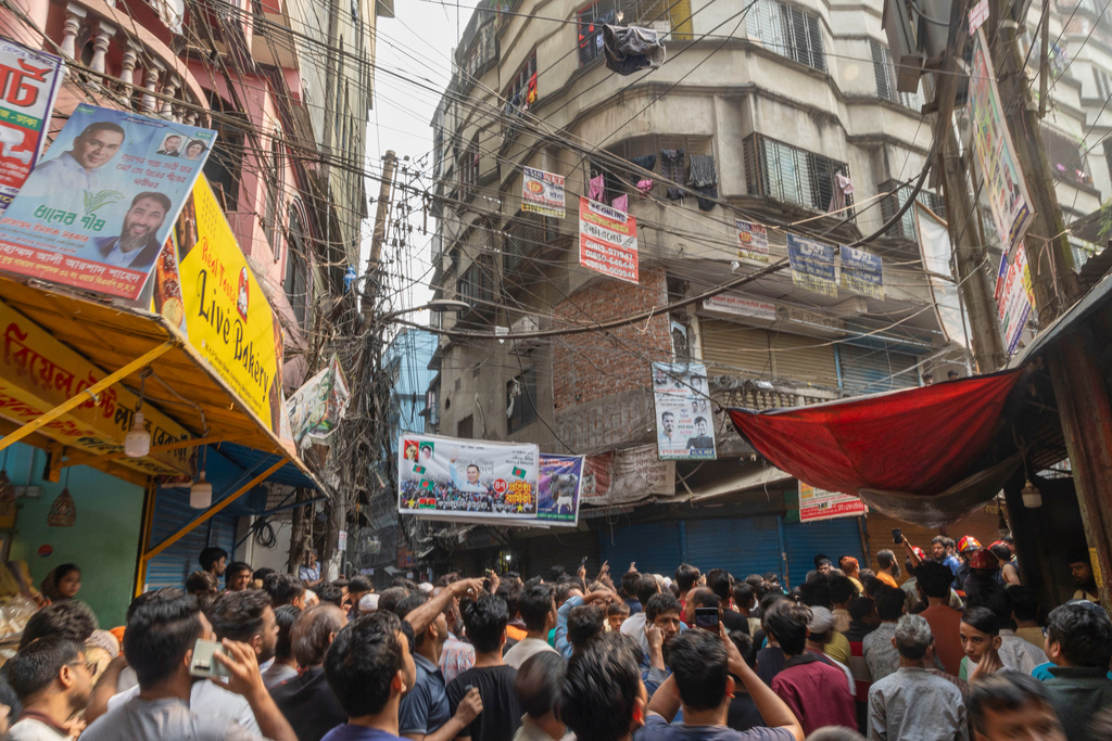 People gather outside a narrow lane in old city area where a roof and wall collapsed, after an earthquake in Dhaka, Bangladesh, Friday, Nov. 21, 2025. (AP Photo/Abdul Goni)