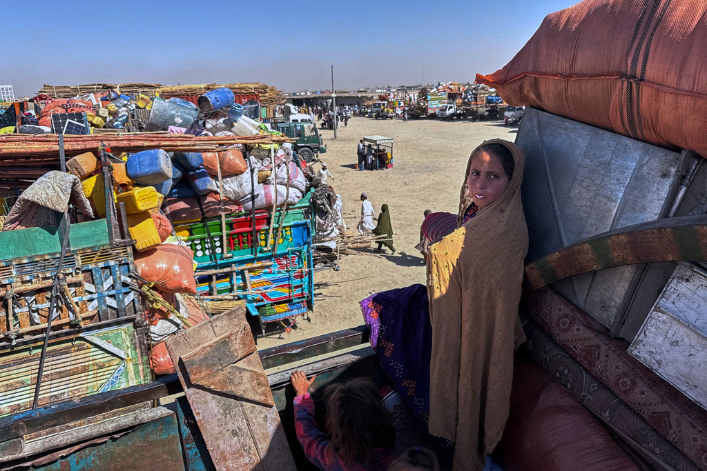 Afghan refugees girls sit over a truck loaded with their belongings as they with others wait for opening of the border crossing point, which closed following Afghan and Pakistani security forces exchanged cross border firing, at a camp in Chaman, Pakistan, Sunday, Oct. 12, 2025. (AP Photo)