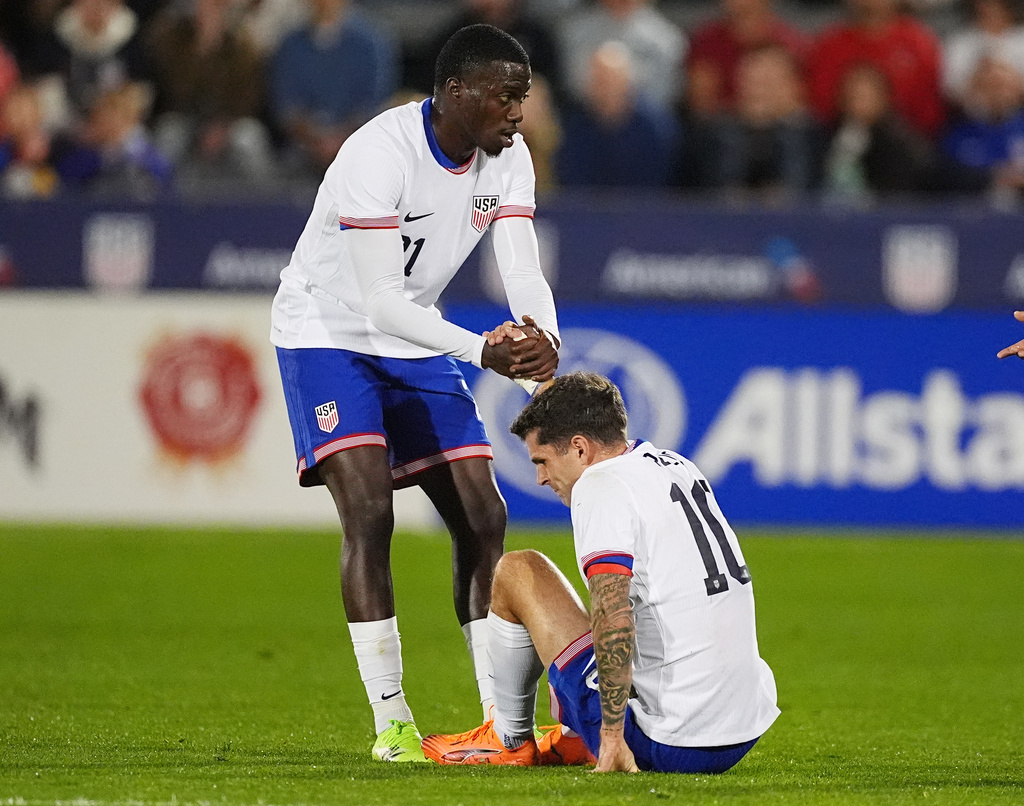 United States forward Tim Weah, left, helps up forward Christian Pulisic after he was injured against Australia in the first half of an international friendly soccer match Tuesday, Oct. 14, 2025, in Commerce City, Colo. (AP Photo/David Zalubowski)