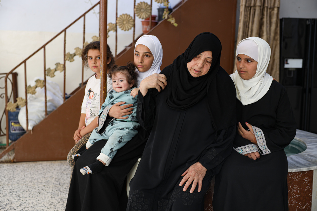 Sabah al-Sheikh al-Kilani, the mother of Khaled al-Masoud, sits with several of his daughters at the family home after he was killed during a raid in the town of al-Dumayr, in the Damascus countryside, Syria, Oct. 28, 2025. (AP Photo/Omar Albam)