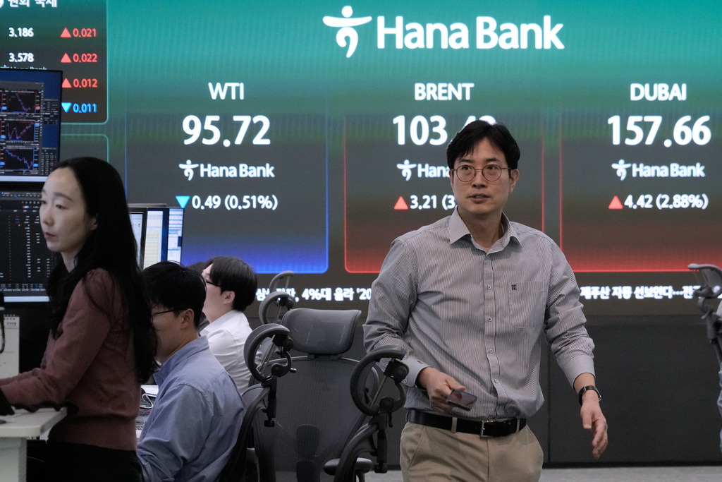 A currency trader passes by a screen showing international oil prices at the foreign exchange dealing room of the Hana Bank headquarters in Seoul, South Korea, Wednesday, March 18, 2026. (AP Photo/Ahn Young-joon)