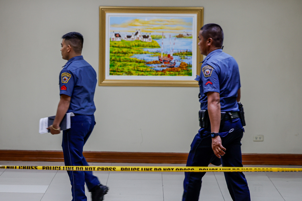 Police personnel walk behind a cordoned-off area inside the Philippine Senate premises in Pasay City Thursday, May 14, 2026, where gunshots were fired Wednesday in connection with a senator who was issued a warrant of arrest by the International Criminal Court. (AP Photo/Gerard Carreon)