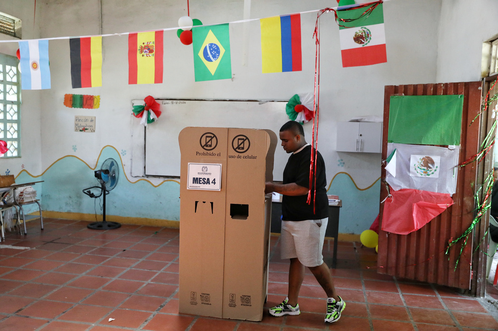 A voter marks his ballot in a classroom decorated with flags of countries participating in the World Cup serving as a polling station during the presidential runoff election in Santander de Quilichao, Colombia, Sunday, June 21, 2026. (AP Photo/Santiago Saldarriaga)