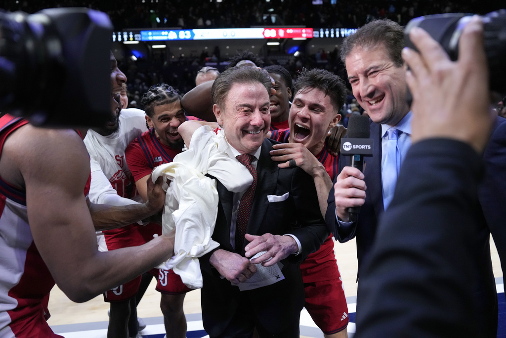 St. John's head coach Rick Pitino, center, is congratulated by his team after earning his 900th career coaching win against Xavier, Saturday, Jan. 24, 2026, in Cincinnati. (AP Photo/Kareem Elgazzar)