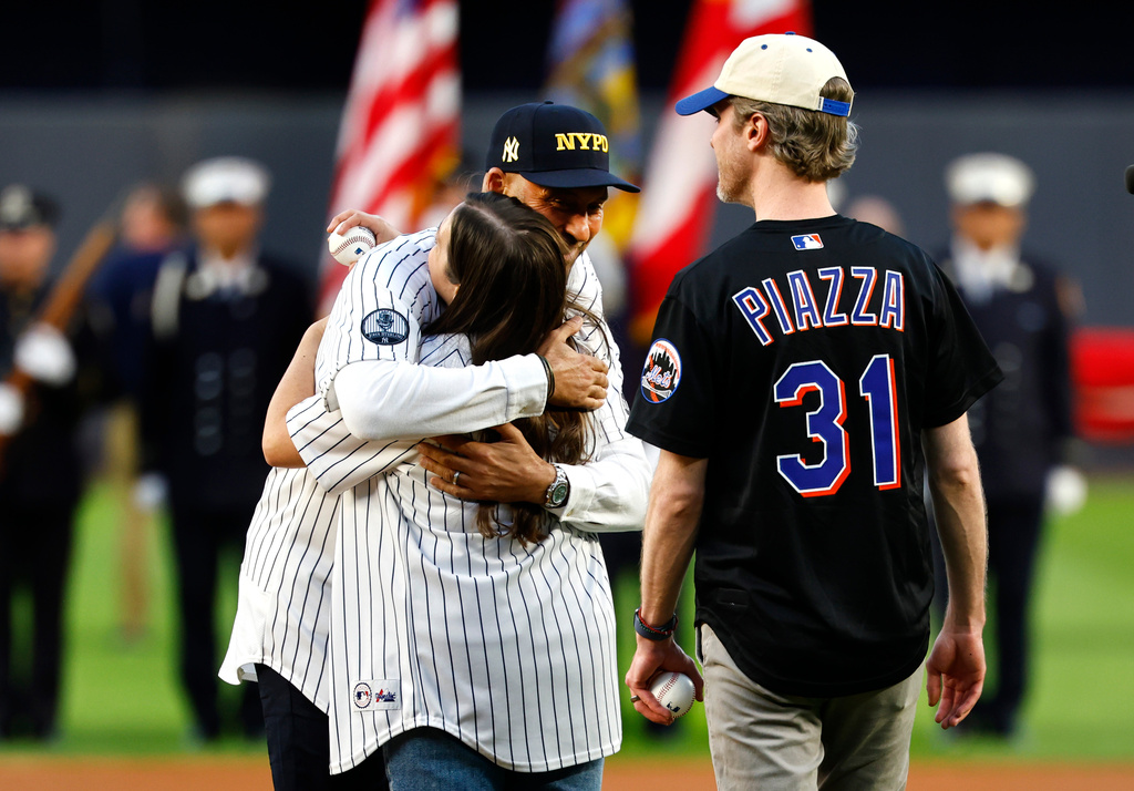 Derek Jeter hugs Brielle Saracini before she throws out the ceremonial first pitch with husband Sean McGuire before a baseball game between the New York Yankees and the New York Mets, Friday, Sept. 11, 2026, in New York. (AP Photo/Noah K. Murray)