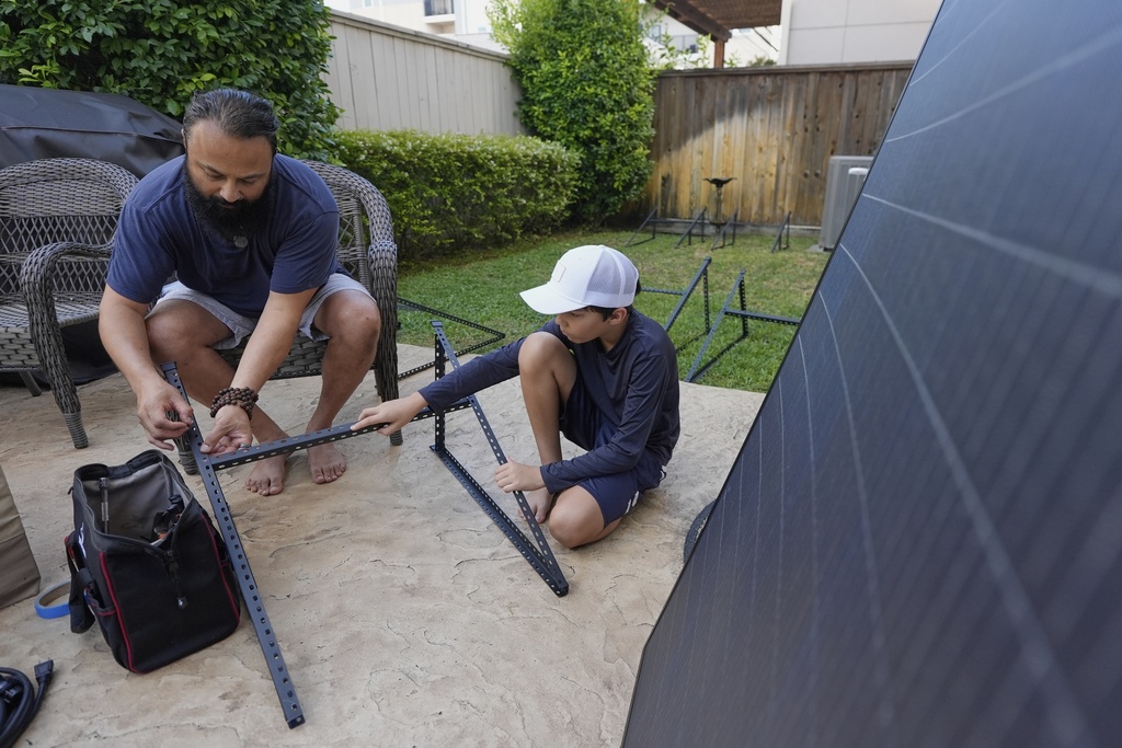 Bhavin Misra, left, and his son, Rumi, 10, assemble a Craftstrom Solar plug-in kit at their home Tuesday, Aug. 5, 2025, in Houston. (AP Photo/David J. Phillip)