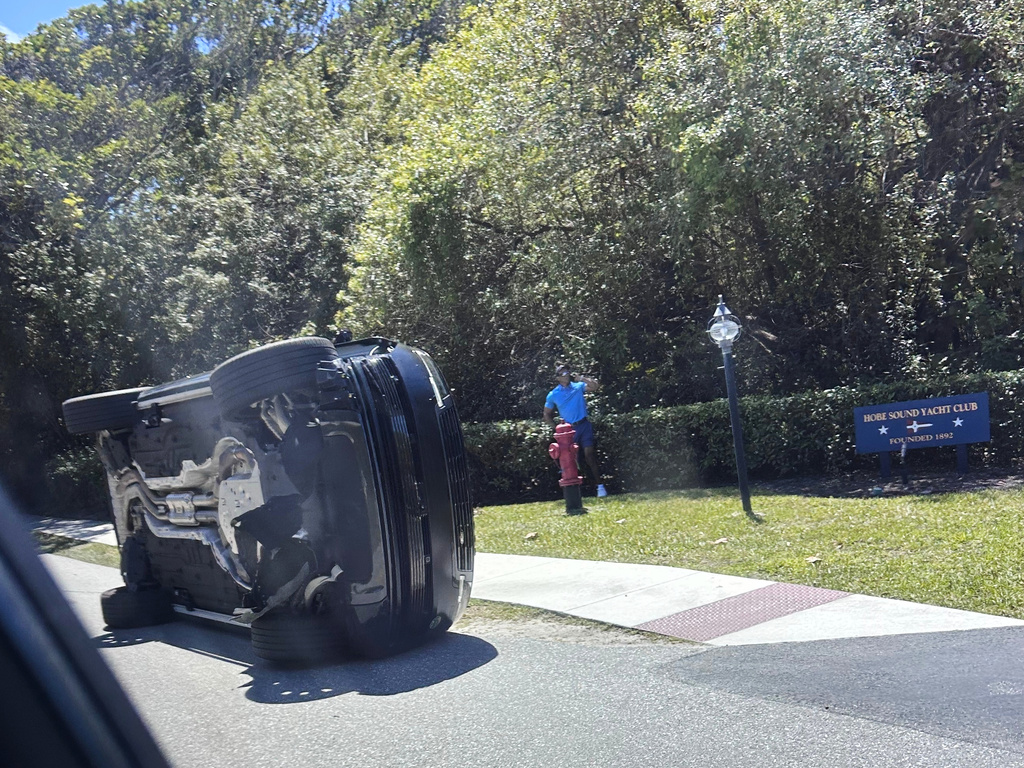 Golfer Tiger Woods stands by his overturned vehicle in Jupiter Island, Fla., Friday, March 27, 2026. (AP Photo/Jason Oteri)