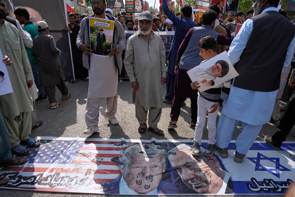 Shiite Muslims walk over the representation of U.S. and Israeli flags with pictures of President Donald Trump and Prime Minister Benjamin Netanyahu during a rally to condemn the killing of Iranian Supreme Leader Ayatollah Ali Khamenei and against the Israeli strikes on Iran, in Islamabad, Pakistan, Friday, March 6, 2026. (AP Photo/Anjum Naveed)