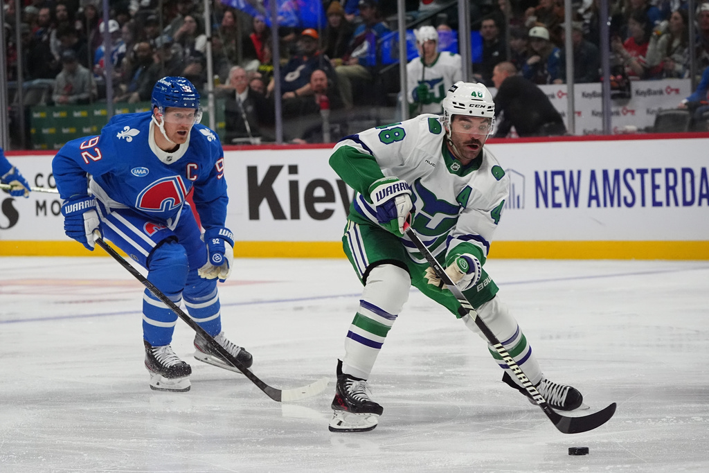 Carolina Hurricanes left wing Jordan Martinook, right, drives to the net past Colorado Avalanche left wing Gabriel Landeskog in the second period of an NHL hockey game Thursday, Oct. 23, 2025, in Denver. (AP Photo/David Zalubowski)