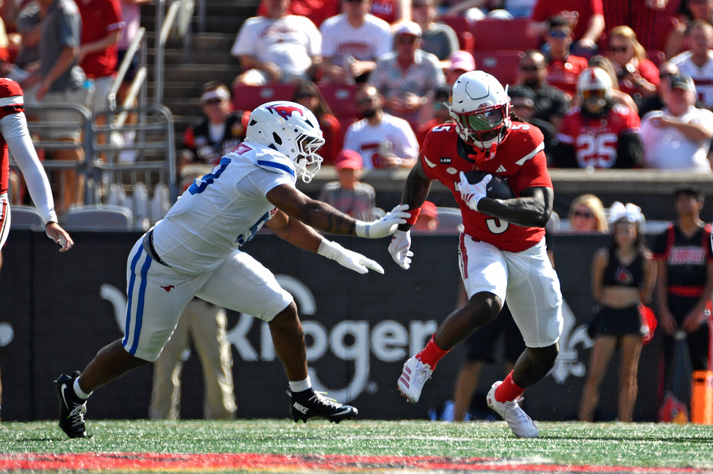 Louisville running back Keyjuan Brown (5) is chased by SMU defensive end Aakil Washington, left, during the first half of an NCAA college football game in Louisville, Ky., Saturday, Sept. 19, 2026. (AP Photo/Timothy D. Easley)