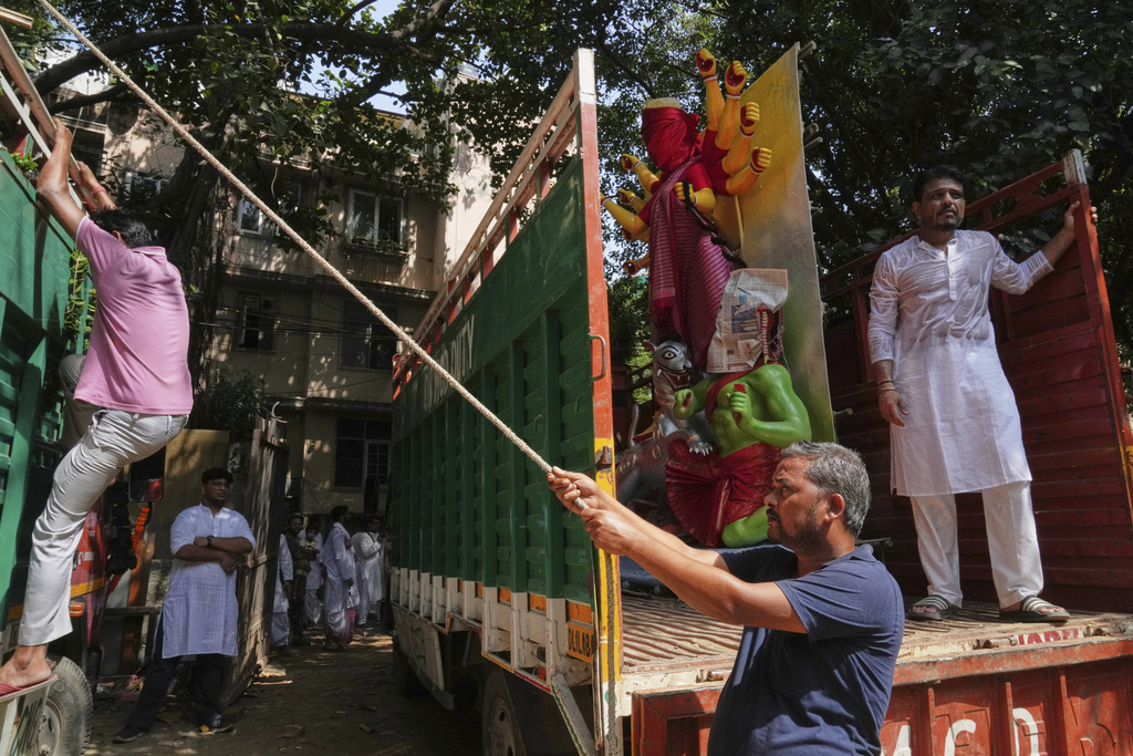 Workers use ropes to secure an idol of the Hindu goddess Durga on a truck as it is transported to a place of worship ahead of the Durga Puja festival in New Delhi, India, Sunday, Sept. 21, 2025. (AP Photo/Manish Swarup)
