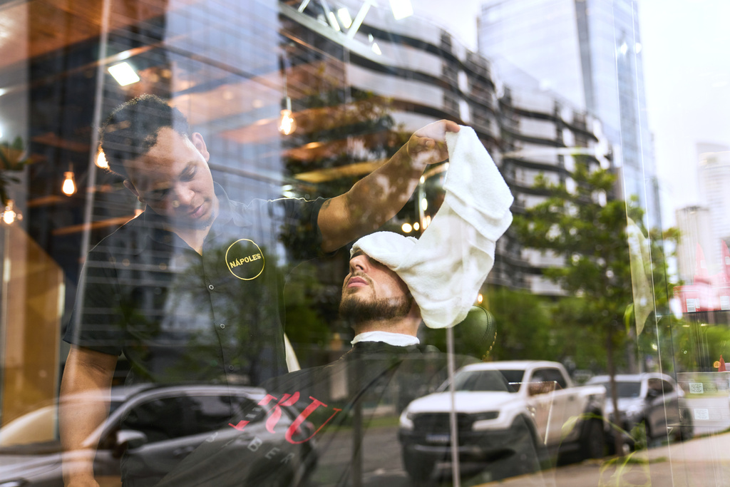 A barber tends to a customer at a barbershop in the Puerto Madero neighborhood of Buenos Aires, Argentina, Friday, Oct. 24, 2025. (AP Photo/Rodrigo Abd)